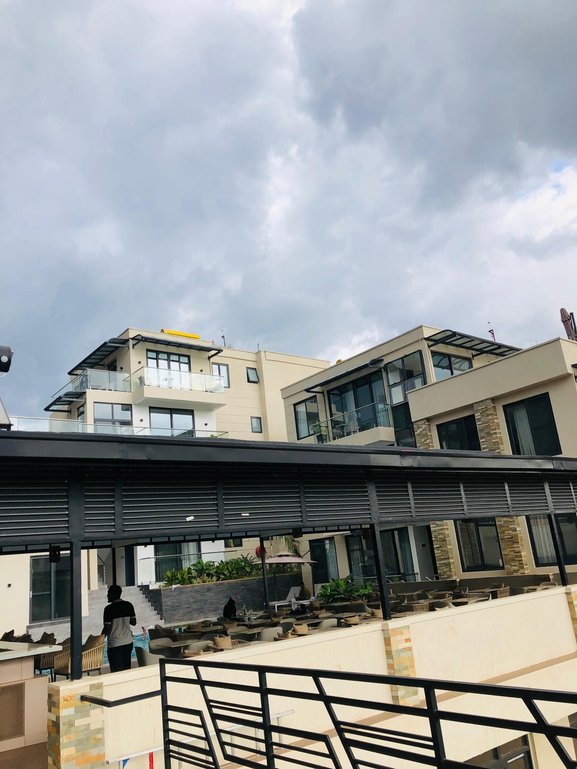 A modern building with multiple floors, large windows, and a covered outdoor area with seating and a pool.
