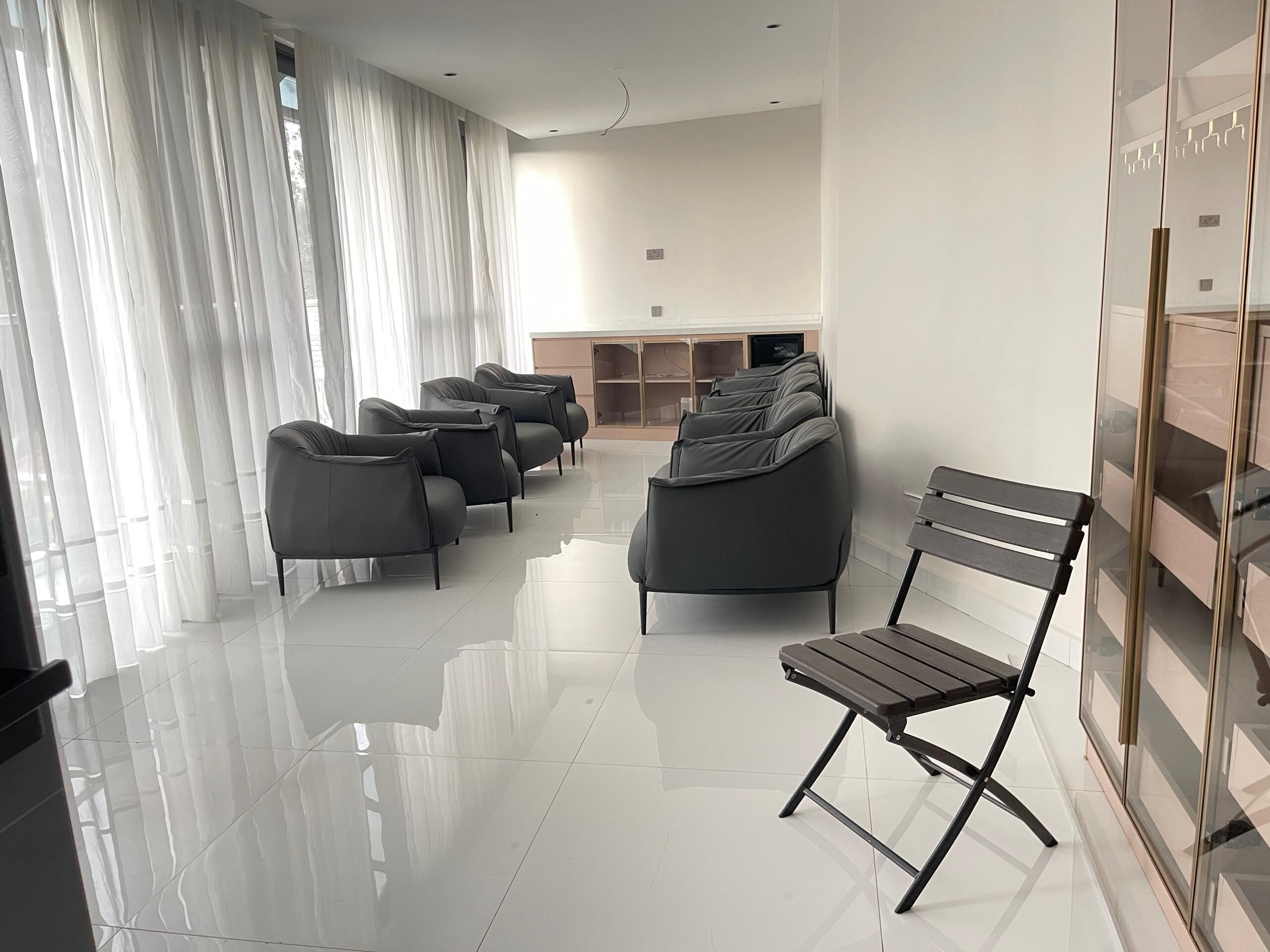 Una sala de estar moderna con un conjunto de sofá, un banco y un aparador de vidrio.
