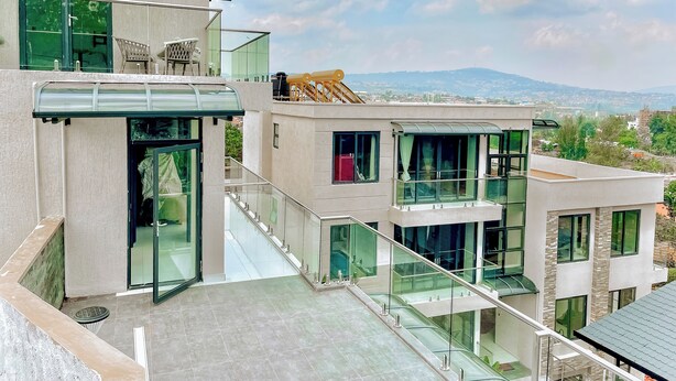 Un bâtiment moderne à plusieurs étages, doté de balustrades en verre et offrant une vue sur un paysage lointain.