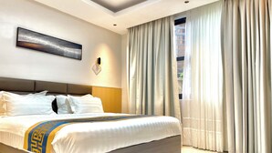 Une chambre d’hôtel moderne avec un grand lit, une tête de lit, une œuvre d’art accrochée au mur et une fenêtre avec des rideaux.
