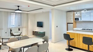 Un salon moderne comprenant un coin repas, un téléviseur et une cuisine équipée d’un four à micro-ondes.
