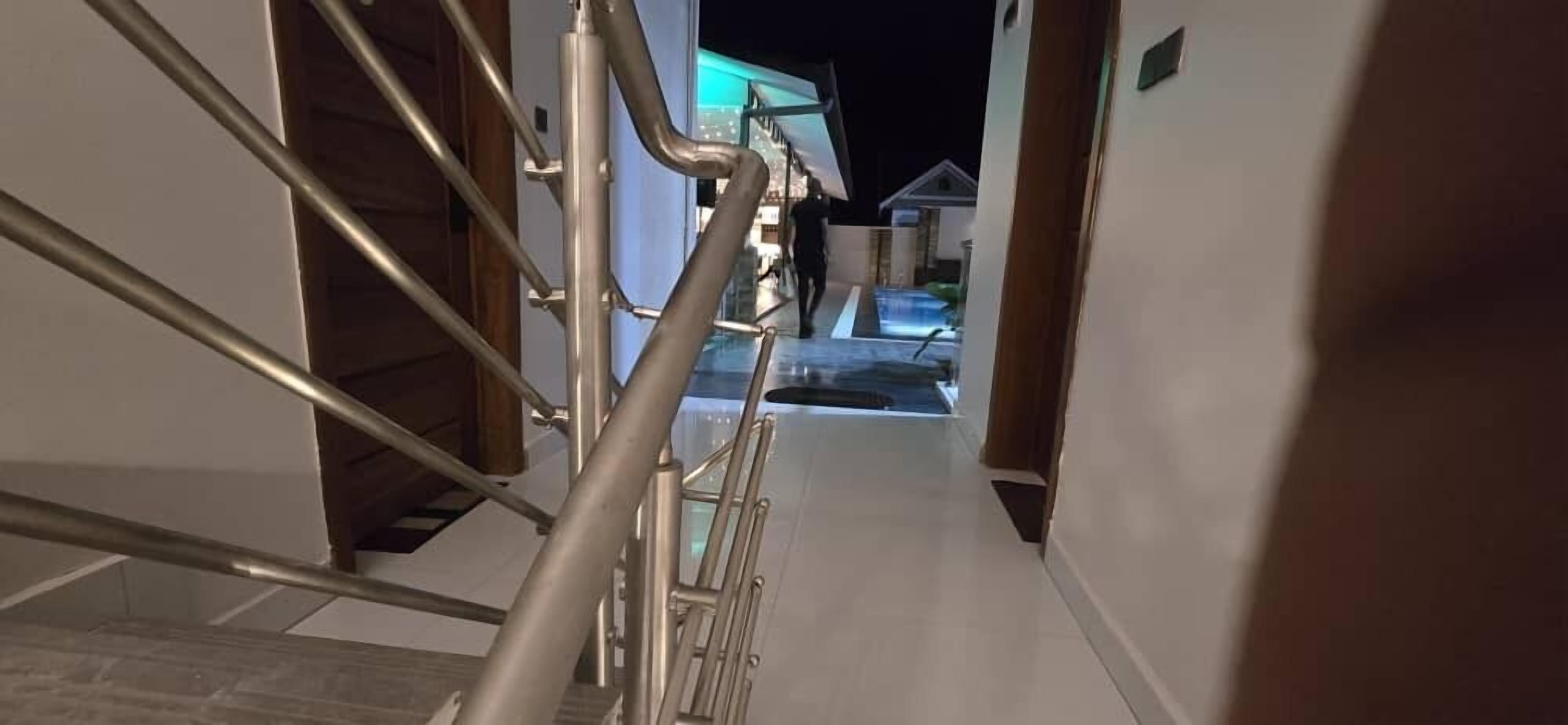 A hallway with a metal staircase leading to a pool area.