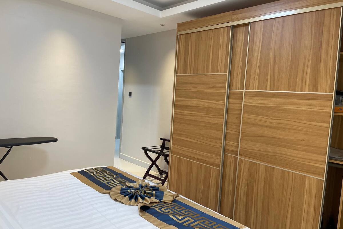 A hotel room with a bed, a wooden wardrobe, and a small table.