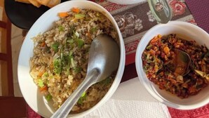 Un tavolo imbandito con diversi piatti, tra cui pane fritto, zuppa, riso e un contorno.