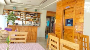 Zona pranzo con tovaglia a scacchi, sedie di legno e angolo bar con scaffali pieni di bottiglie e bicchieri.