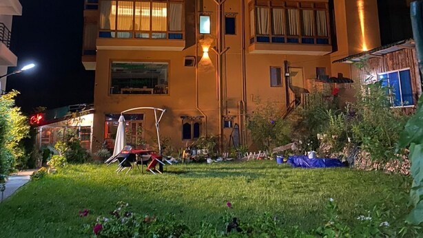 Un hotel a più piani con una facciata ben illuminata, un ingresso facilmente riconoscibile e un’area giardino con piante in vaso.
