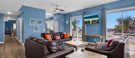 A spacious living area with leather sofas, a coffee table, and ceiling fans.