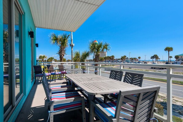 A covered outdoor seating area with a view of the street and palm trees.