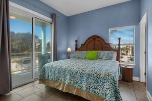 Une chambre à coucher comprenant un lit, une table de chevet, une lampe, une fenêtre avec des stores et une vue sur l’extérieur.