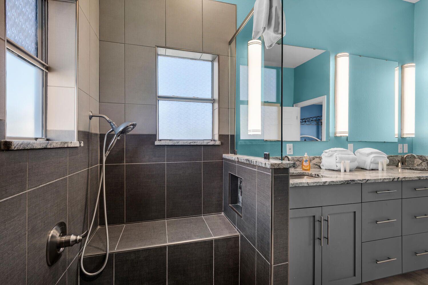 Un baño moderno con cabina de ducha, tocador con lavabo y un espejo grande.