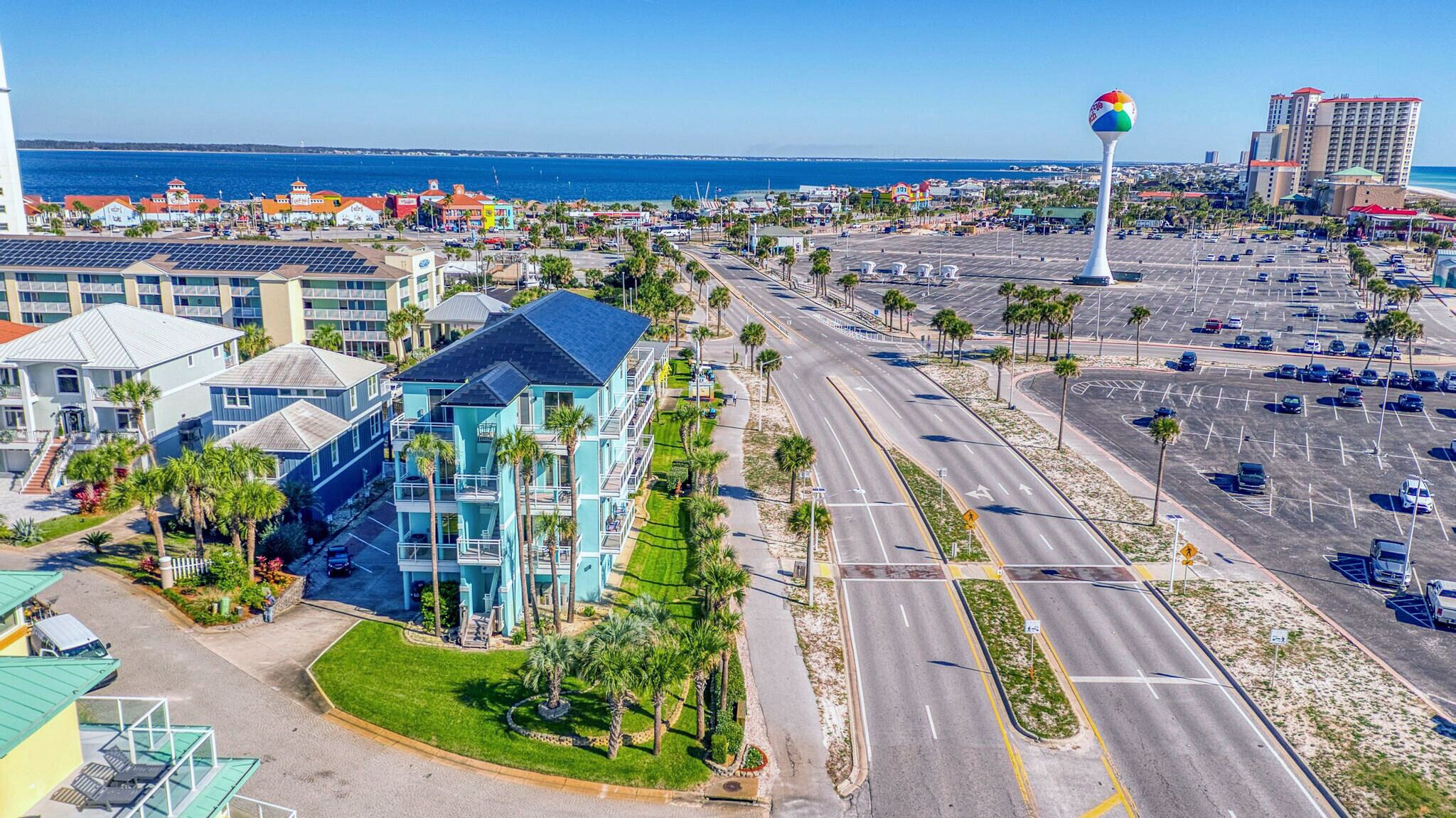 Un hotel costero con varios pisos, un estacionamiento y vista a la playa y al océano.