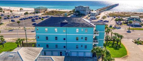 Un edificio de varios pisos con techo plano, cerca de una playa y un muelle.