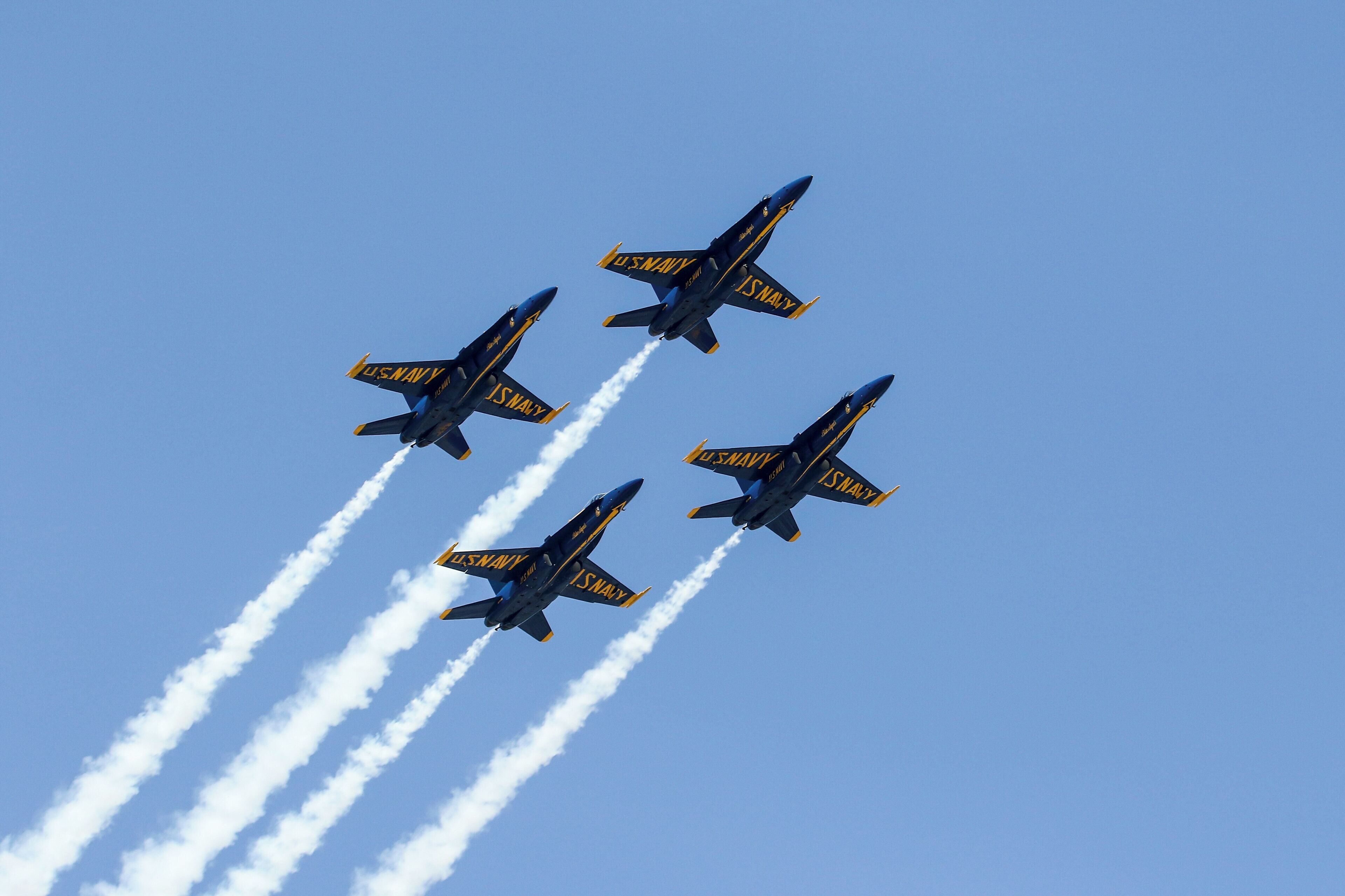 Cuatro aviones de los Blue Angels de la Marina estadounidense volando en formación, dejando estelas de humo.