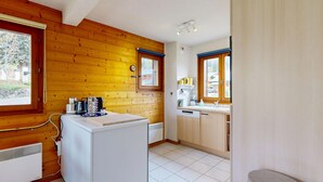 Een kleine keuken met houten wanden, een inbouwkoelkast en een raam met uitzicht op een woonwijk.