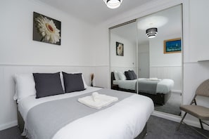 Una camera d'albergo ordinata con un letto grande, uno specchio e una sedia.