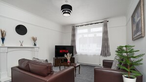 A modern living room with a fireplace, a television, and a potted plant. - 2-bed Flat, Wishaw, Free Parking, Family-friendly (Wishaw)