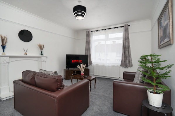 A modern living room with a fireplace, a television, and a potted plant. - 2-bed Flat, Wishaw, Free Parking, Family-friendly (Wishaw)