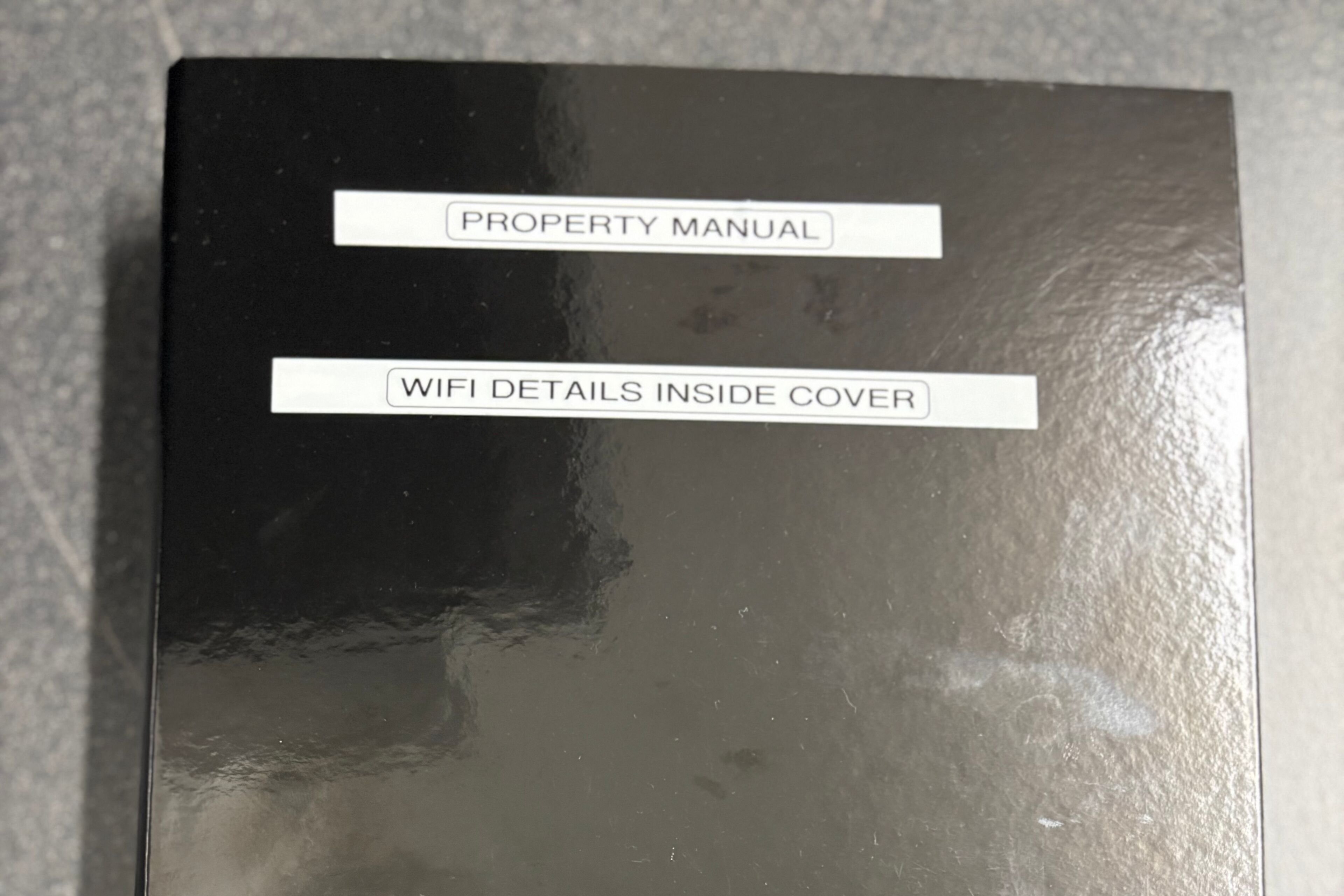 A black box with labels reading "PROPERTY MANUAL" and "WIFI DETAILS INSIDE COVER".