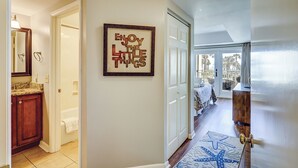 A hallway with a framed inspirational quote, a bathroom with a vanity, and a view of a balcony with outdoor furniture. - Sunset Rentals | Shorewood 134 (Hilton Head Island)