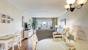 A spacious living room with a dining area, a television, and a balcony with a view. - Sunset Rentals | Shorewood 134 (Hilton Head Island)