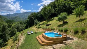 A wooden hot tub surrounded by a wooden deck, with a grassy area and a few lounge chairs. - La Casa Del Tiglio (Borgo San Lorenzo)