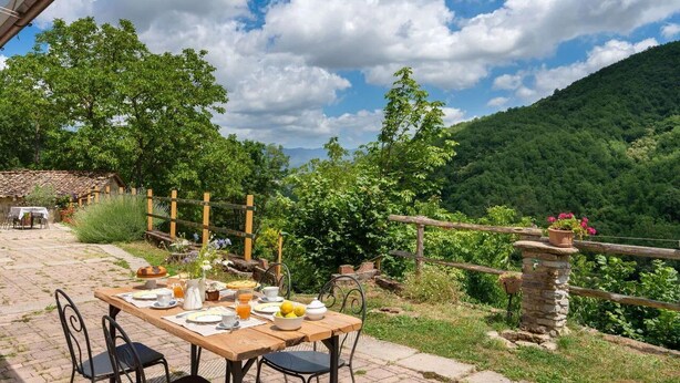 A wooden table set for breakfast with plates, cups, and a pitcher of orange juice, surrounded by chairs. - La Casa Del Tiglio (Borgo San Lorenzo)