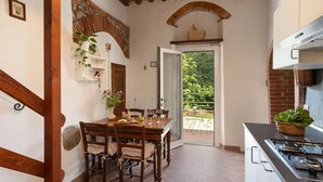 A rustic kitchen with a stone archway, wooden beams, and a view to the outside. - La Casa Del Tiglio (Borgo San Lorenzo)