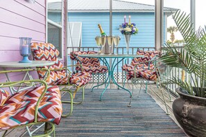 Relax in this inviting outdoor seating area with a metal table, matching chair, and patterned cushions.