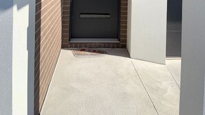 Ein modernes Äußeres mit einer dunklen Tür mit der Aufschrift '12', einem kleinen Eingangsbereich und einem Betonweg.