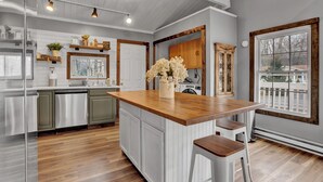 A kitchen with a wooden island, white cabinetry, and a large window. - Beautiful Poconos Getaway with Game room ,Hot Tub, and Fire pit (Tobyhanna)