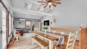 A spacious dining area with a wooden table and benches, a ceiling fan, and a view of the living room. - Beautiful Poconos Getaway with Game room ,Hot Tub, and Fire pit (Tobyhanna)