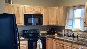 A kitchen with wooden cabinets, a black refrigerator, a microwave, and a stove.