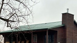 A log cabin with a porch and a chimney.