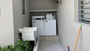 A compact laundry area with two washing machines and a small sink.