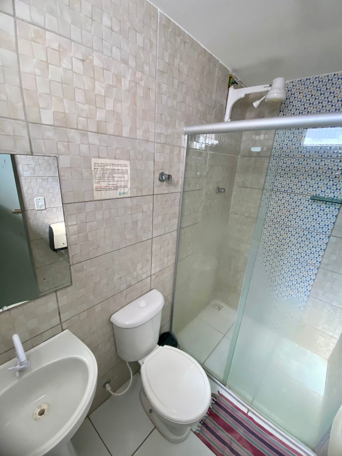 Een badkamer met toilet, wastafel en douchecabine met glazen wanden.