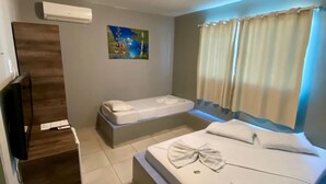 Een hotelkamer met een groot bed, een kleiner bed, een flatscreen televisie en een schilderij aan de muur.