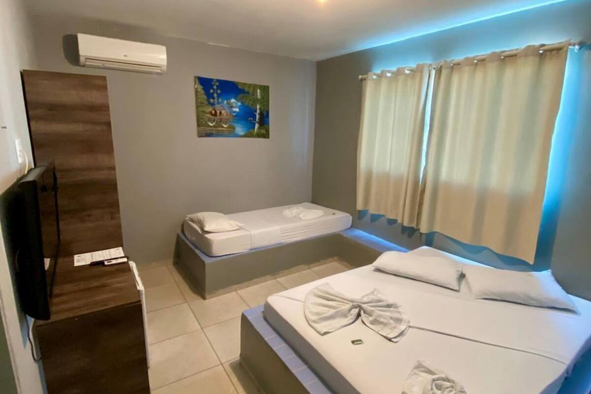 A hotel room with a large bed, a smaller bed, a flat-screen TV, and a painting on the wall.