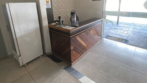 Een keuken met een koelkast, een koffieapparaat en een houten aanrecht.