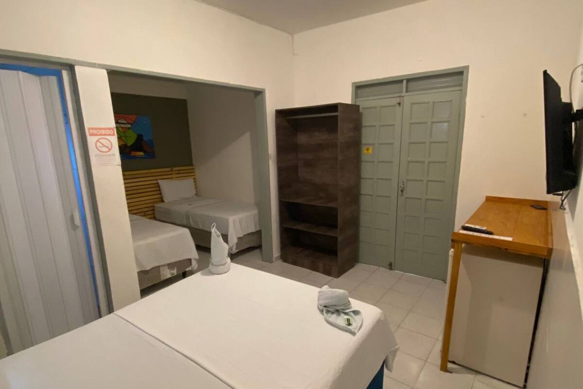 A hotel room with a bed, a desk, a wardrobe, and a television.