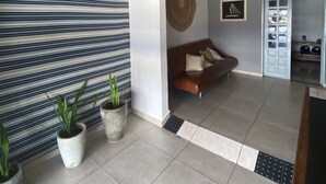 Een modern interieur met een gestreepte wand, een bruine bank en potplanten.
