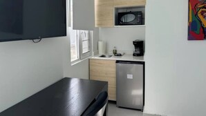 A compact kitchen with a microwave, coffee maker, and a small refrigerator.