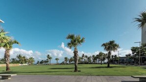 A paved plaza with palm trees and a clear blue sky. - Beach House Walk to The Beach #8 (San Juan)