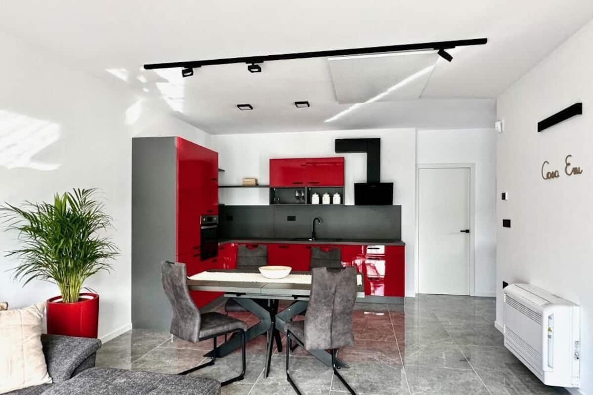 A modern kitchen with red cabinets, a dining area with a table and chairs, and a white radiator.