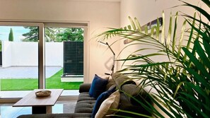 A modern living room with a sofa, a coffee table, and a large potted plant. - Apartments E&T  (Ankaran)