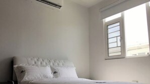 A bedroom with a bed, a nightstand, and a window.