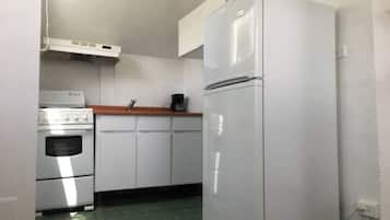 A compact kitchen with a white refrigerator, a stove, and a small countertop.