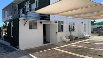 A two-story house with a balcony, a covered patio area, and a small garden.