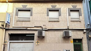 Un edificio con tre persiane chiuse, un'anta di garage e un cancello verde.
