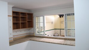 Una cucina con finestra, mensole in legno e uno schienale piastrellato.
