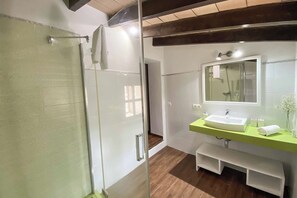 A modern bathroom with a glass shower enclosure, a white sink with a green countertop, and a large mirror above the sink.